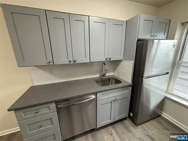 a kitchen with stainless steel appliances granite countertop a refrigerator a sink and white cabinets