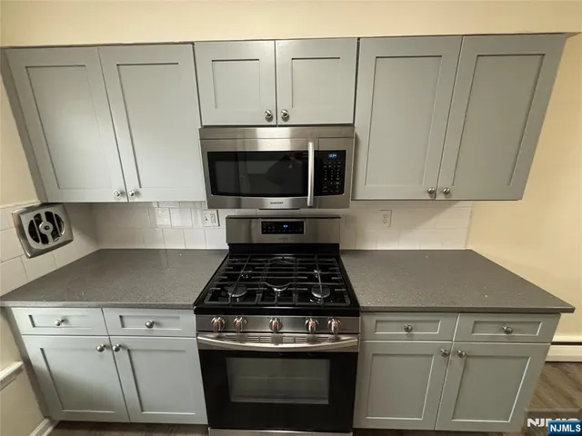 a kitchen with granite countertop white cabinets and stainless steel appliances