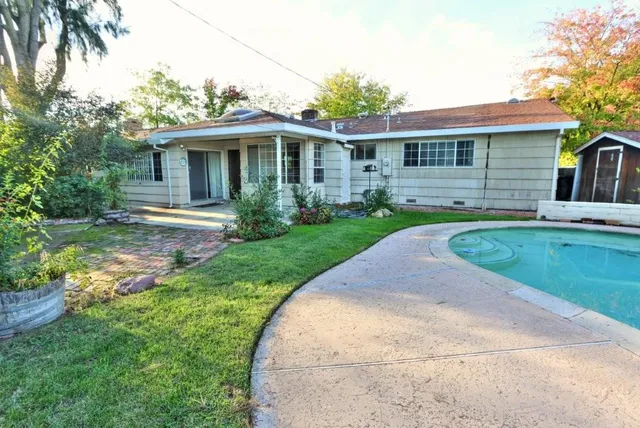 a view of a yard in front of a house with large windows