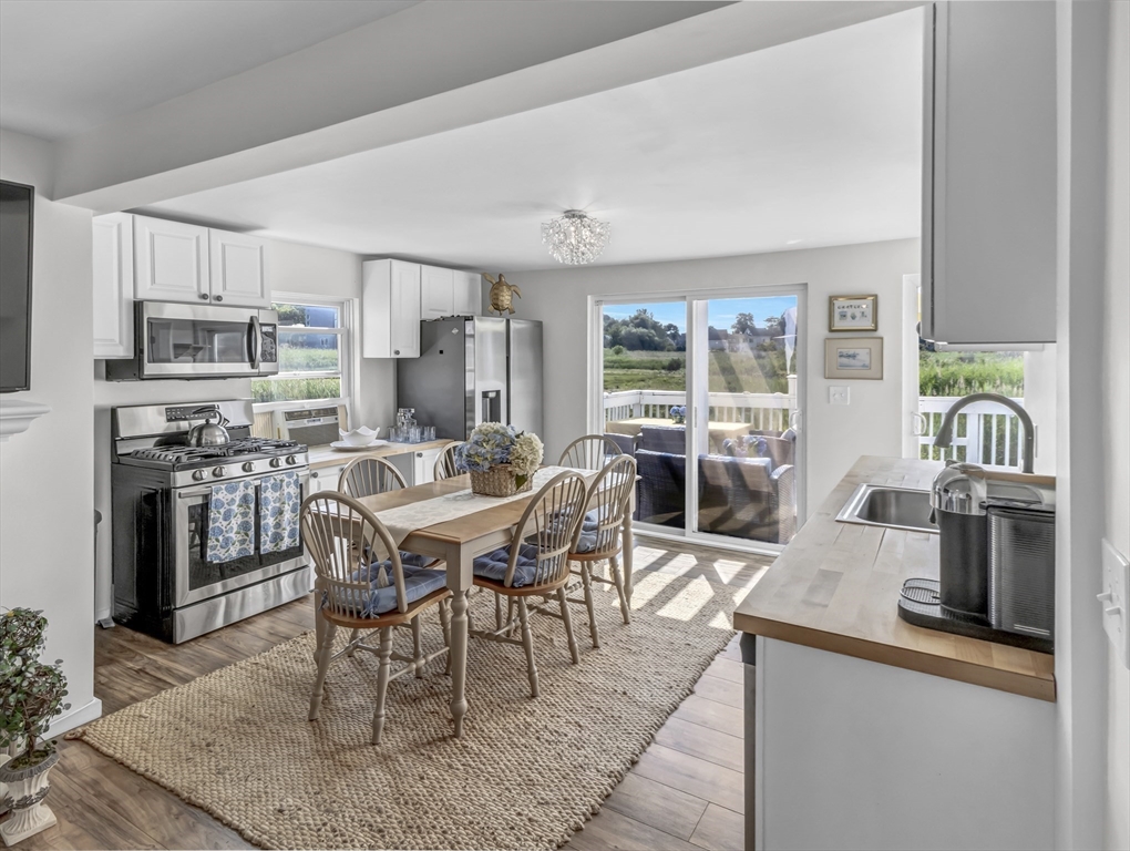 3 Bay View Street Hull, MA 02045 - Photo 12 of 39 a dining room with stainless steel appliances kitchen island granite countertop a table chairs a sink dishwasher and a fireplace