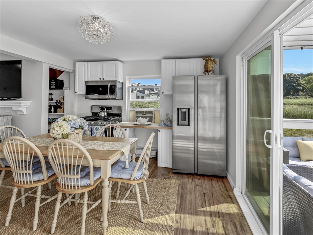 3 Bay View Street Hull, MA 02045 - Photo 9 of 39 a kitchen with stainless steel appliances granite countertop a refrigerator a stove a microwave oven with a dining table and chairs