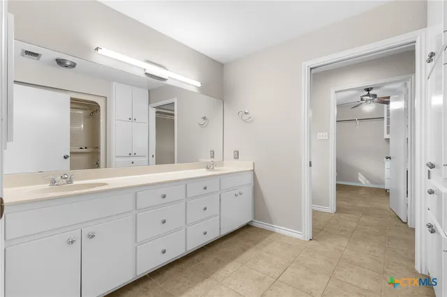 a spacious bathroom with a double vanity sink a mirror and a shower