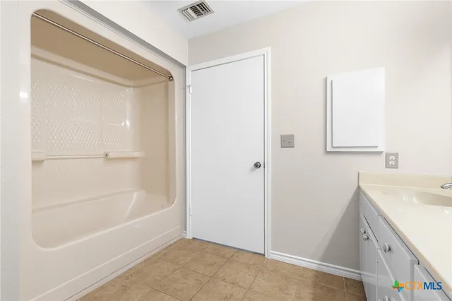 a bathroom with a tub sink vanity and a mirror
