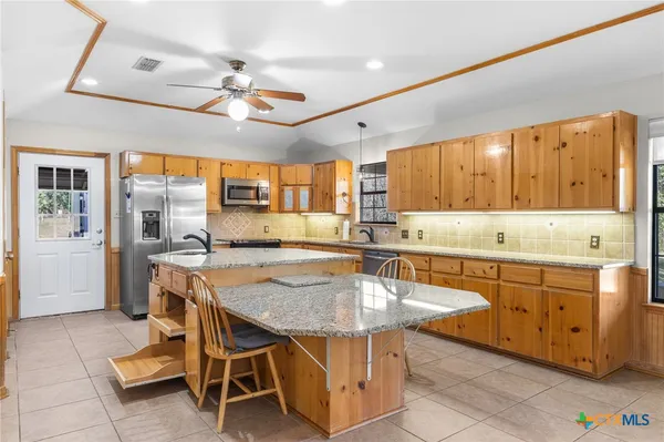 a kitchen with granite countertop a table chairs sink and cabinets