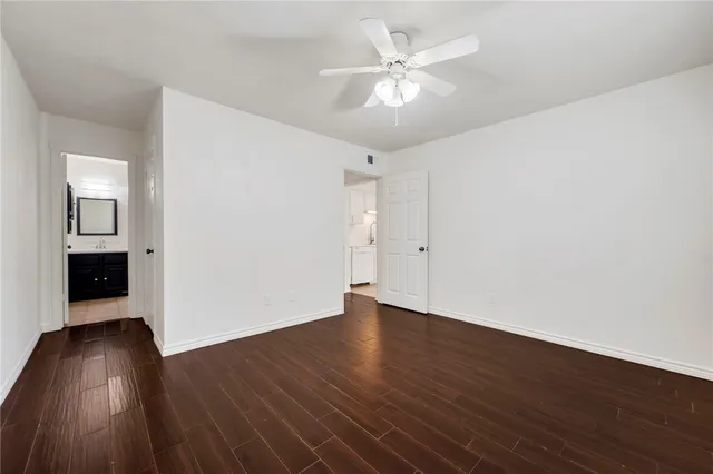 an empty room with wooden floor chandelier fan and windows