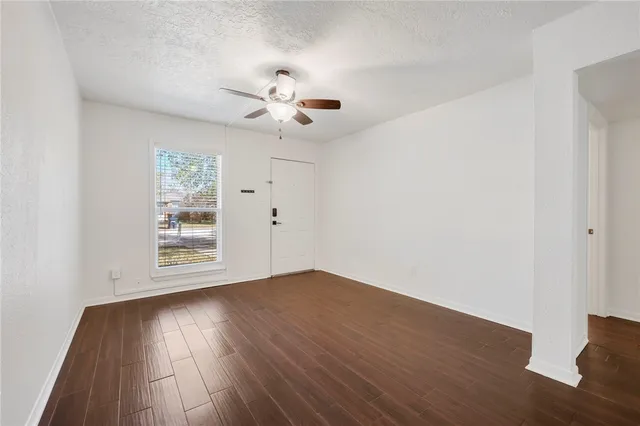 an empty room with wooden floor and windows