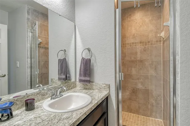 a bathroom with a granite countertop sink a mirror and a shower