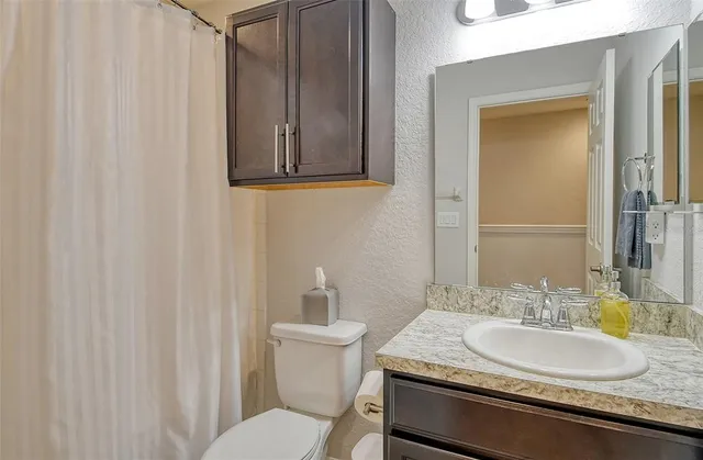 a bathroom with a granite countertop sink and a mirror with toilet