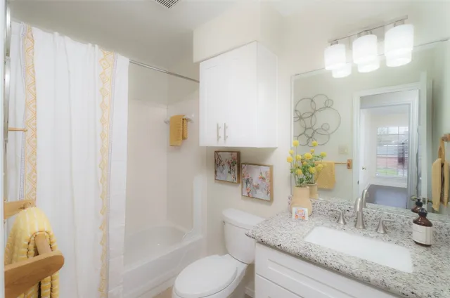 a bathroom with a granite countertop sink and a mirror with toilet