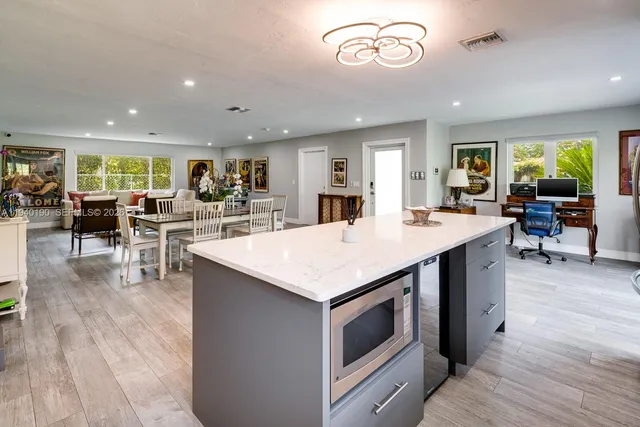 a open kitchen with stainless steel appliances granite countertop a table chairs and a stove
