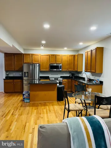 a kitchen with stainless steel appliances kitchen island granite countertop a refrigerator and stove a sink with wooden floor