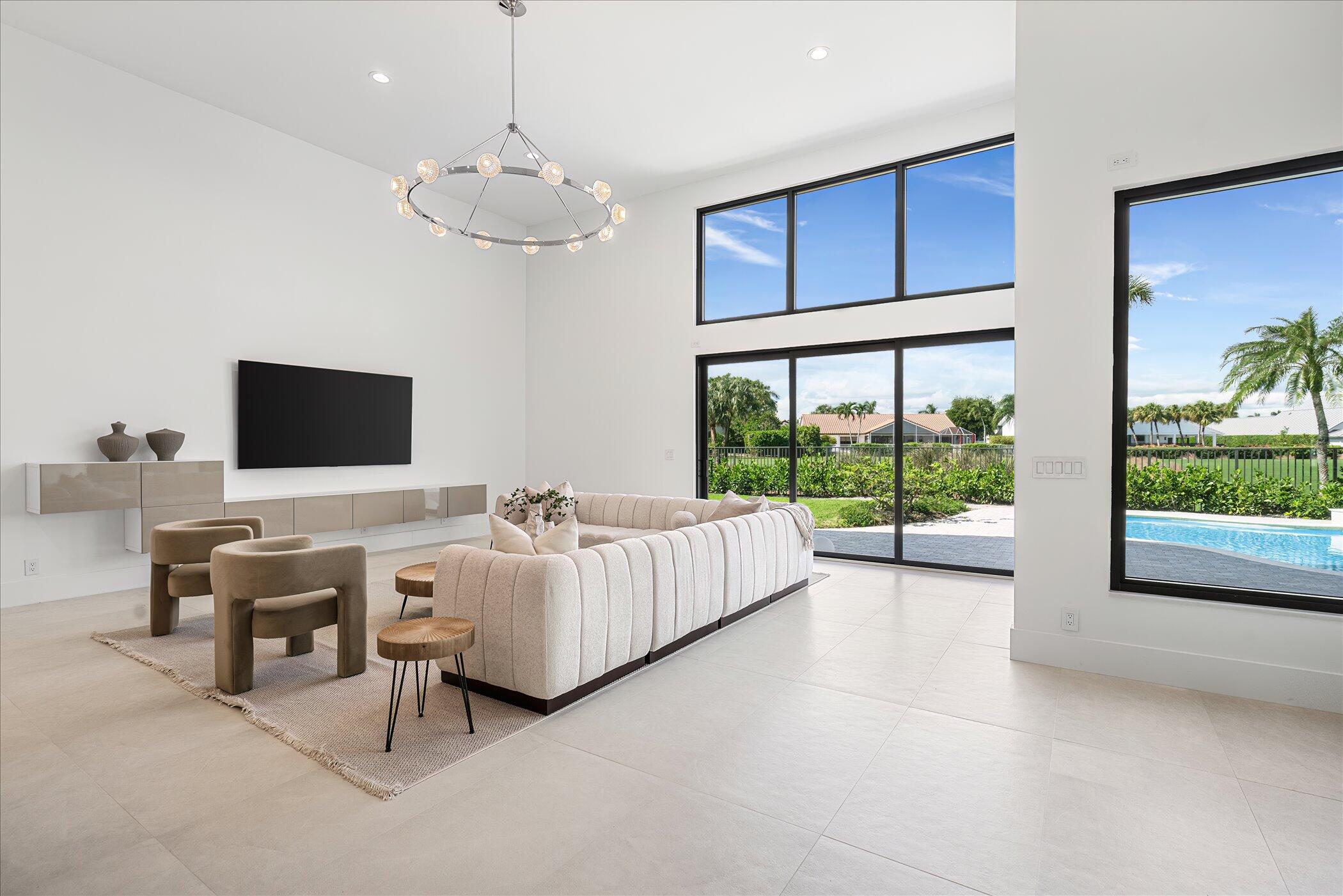 4459 Bocaire Boulevard Boca Raton, FL 33487 - Photo 16 of 72 a living room with furniture a flat screen tv and a floor to ceiling window