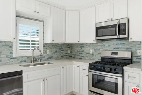 a kitchen with stainless steel appliances a stove a microwave a sink and cabinets