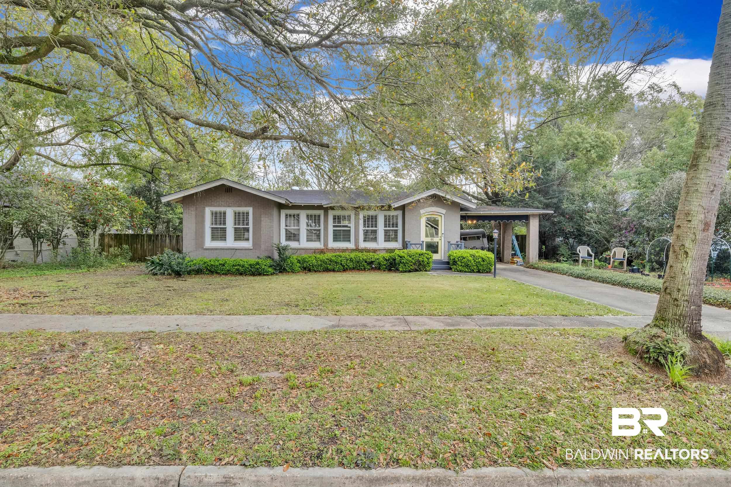 55 Mohawk Street Mobile, AL 36606 - Photo 3 of 28 View of front of house featuring an attached carport, fence, driveway, stucco siding, and a front lawn
