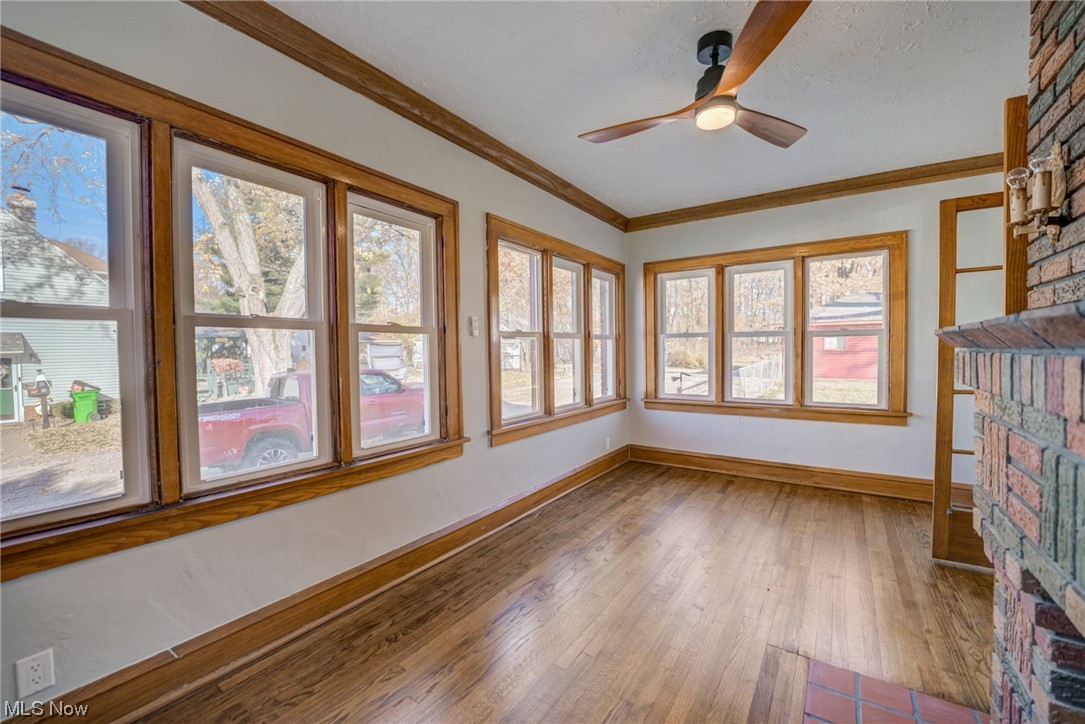 6197 Turney Road Cleveland, OH 44125 - Photo 10 of 35 Unfurnished sunroom featuring a brick fireplace, ceiling fan, and plenty of natural light