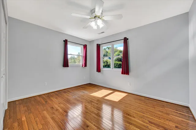 a view of an empty room with a window and wooden floor