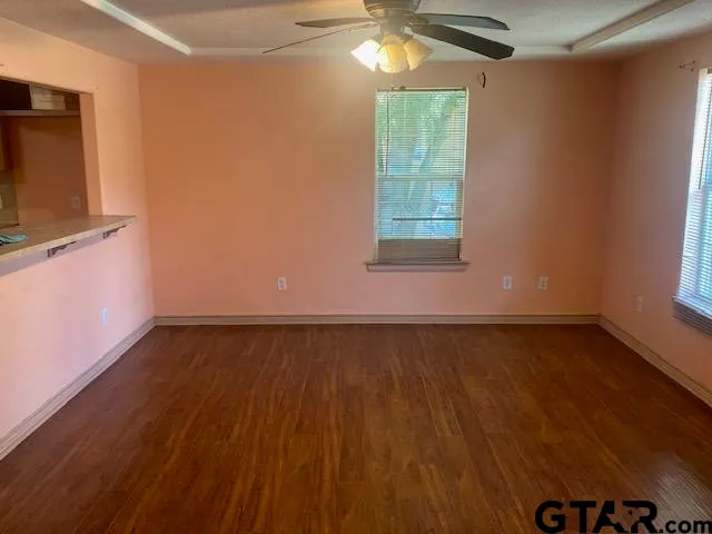 an empty room with wooden floor and windows