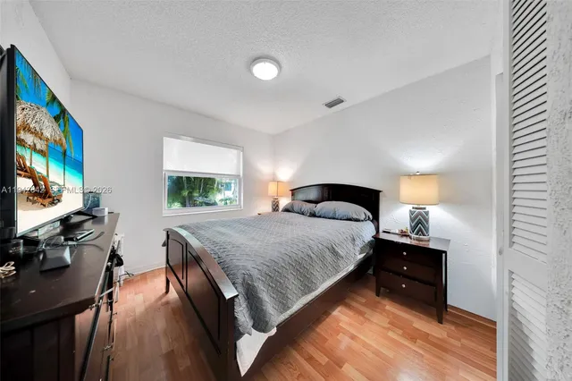 a bedroom with a bed and a flat tv screen on dresser