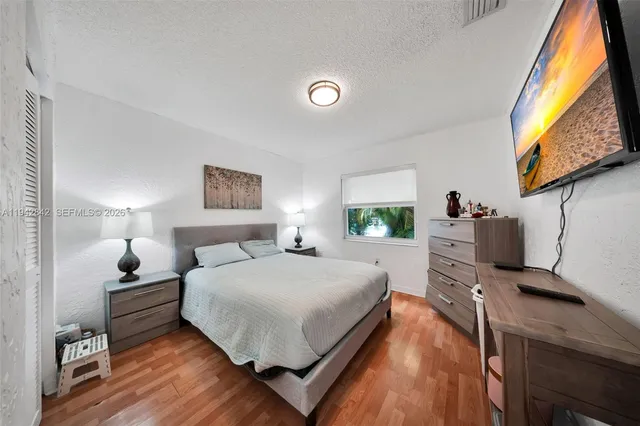 a bedroom with a bed and a flat tv screen on dresser