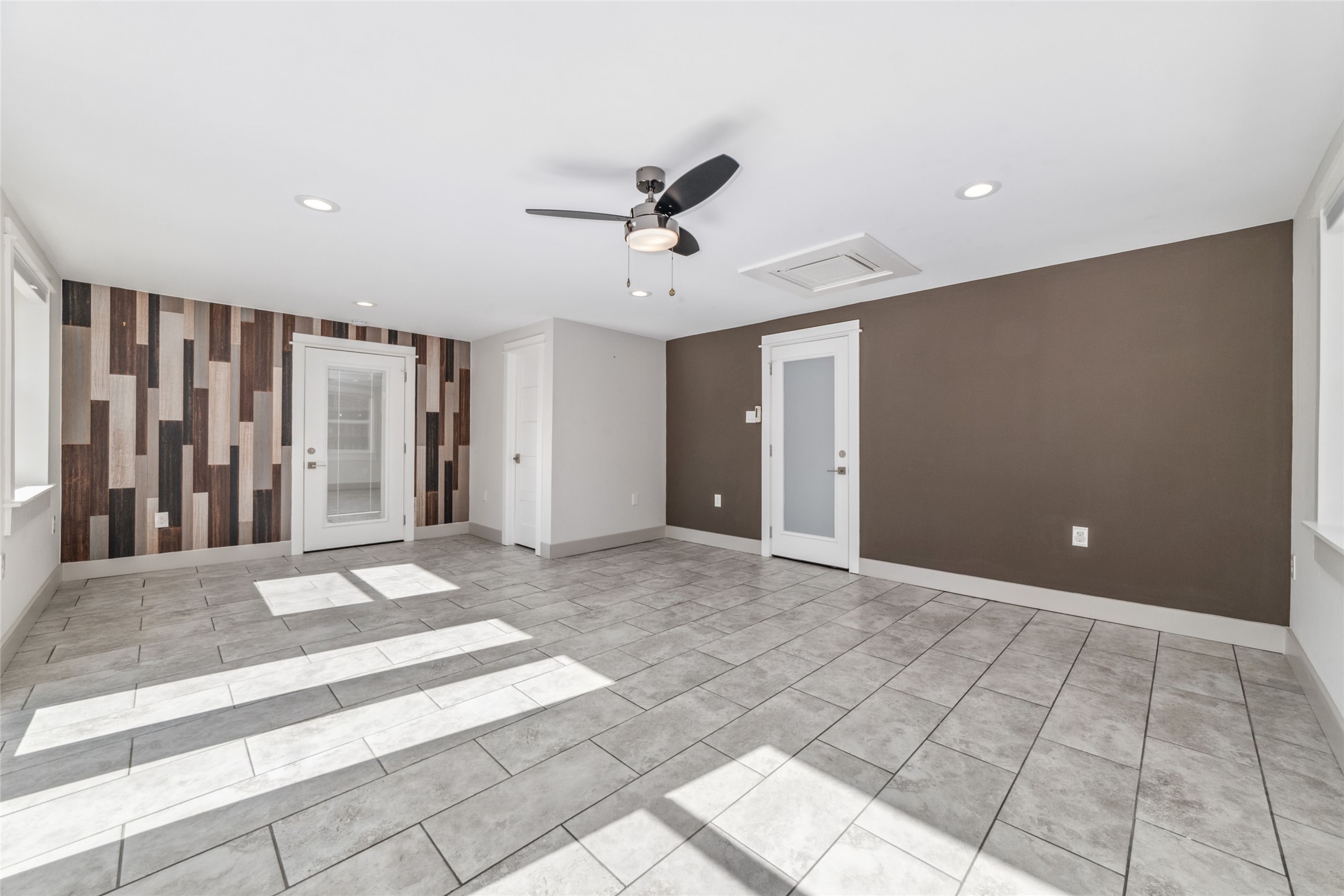 9400 Spring Branch Drive Houston, TX 77080 - Photo 22 of 45 Bright and spacious room featuring modern tile flooring, a stylish accent wall, and ample natural light from multiple windows.
