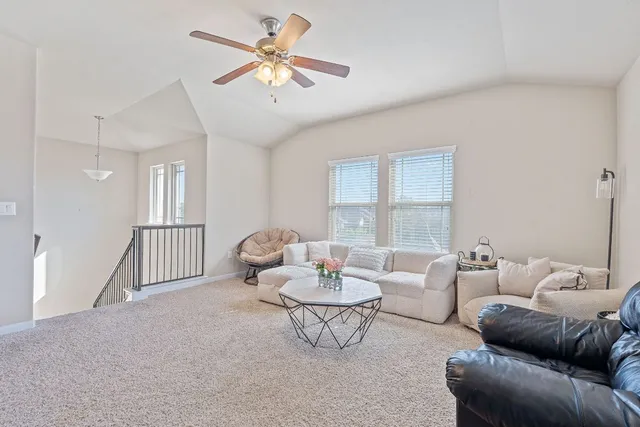 a living room with furniture a ceiling fan a rug and a window