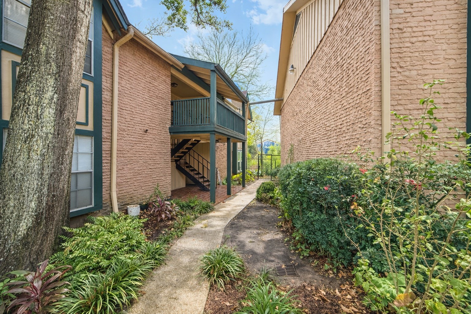 8223 Kingsbrook Road, Unit 215 Houston, TX 77024 - Photo 2 of 20 Walkway to the condo, situated upstairs on the left side of the image, showcasing the property's entrance and surroundings.