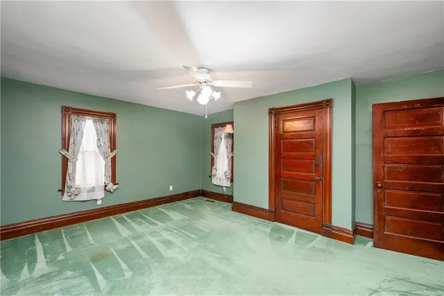an empty room with closet chandelier fan and windows