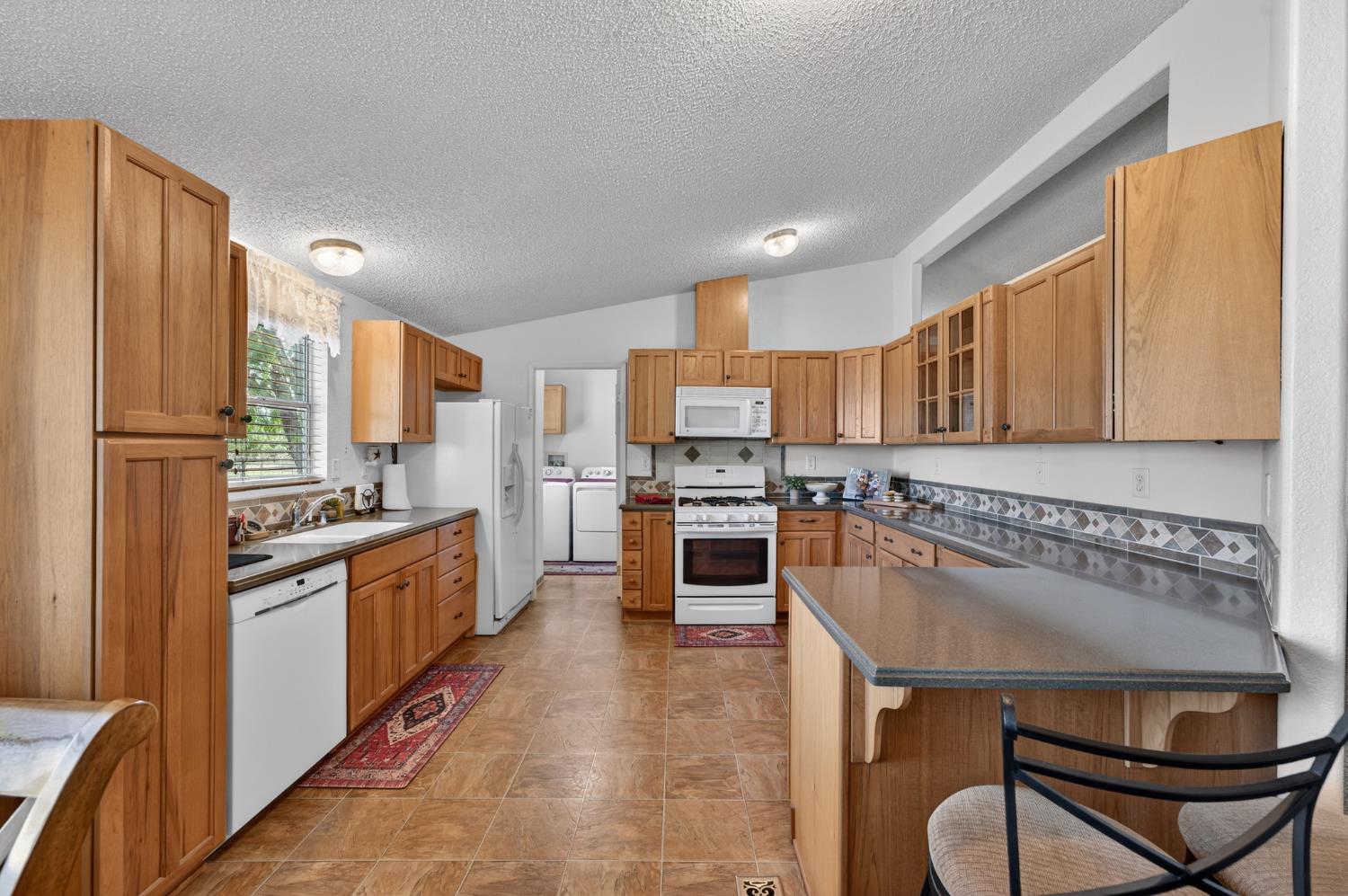 2450 George Road Williams, CA 95987 - Photo 23 of 43 a kitchen with stainless steel appliances granite countertop a refrigerator a stove top oven and white cabinets