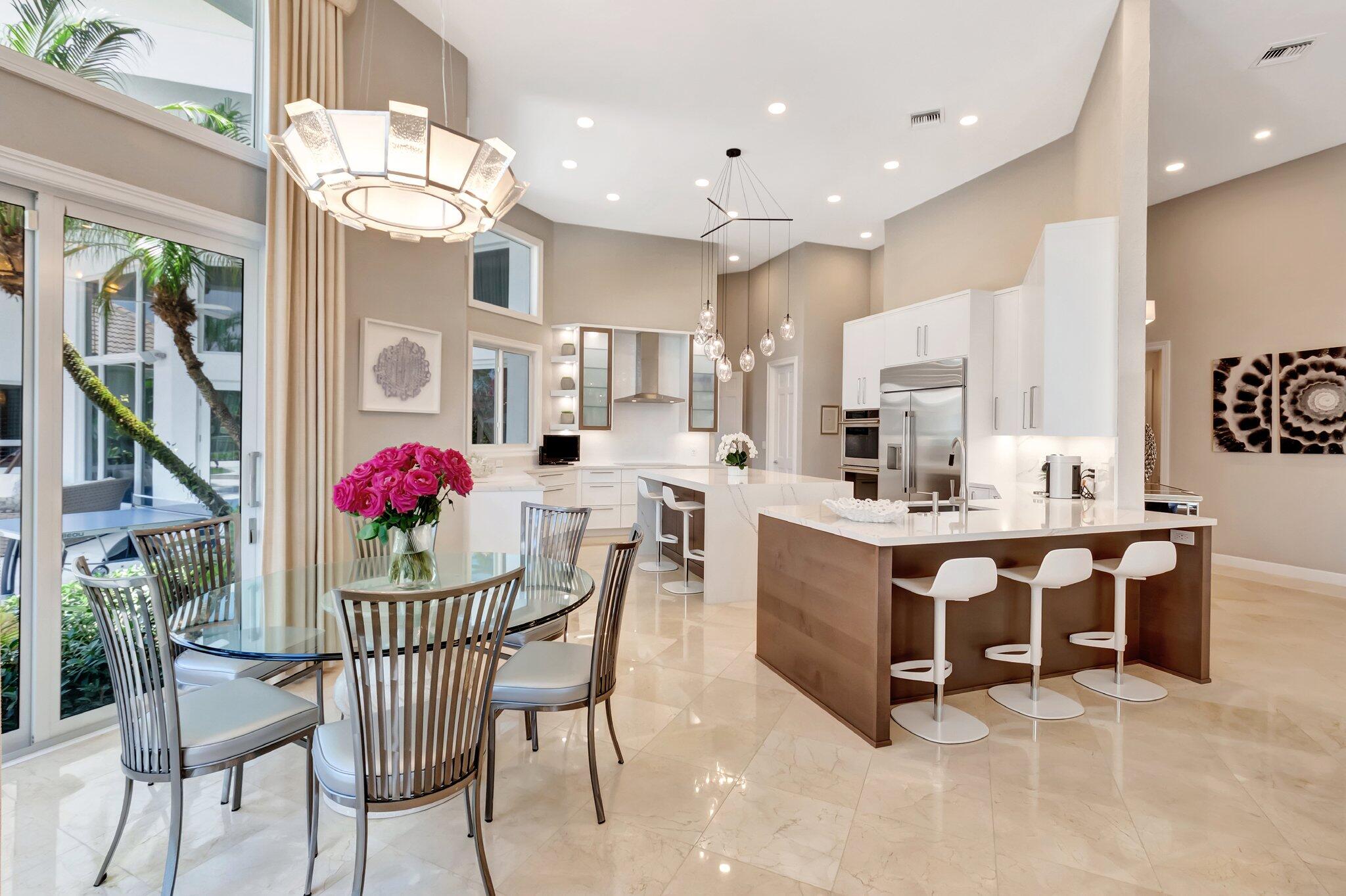 2599 Northwest 63rd Lane Boca Raton, FL 33496 - Photo 17 of 81 a kitchen with stainless steel appliances kitchen island granite countertop a dining table chairs and white cabinets