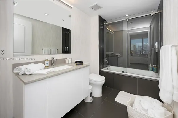 a bathroom with a granite countertop sink toilet mirror and bathtub