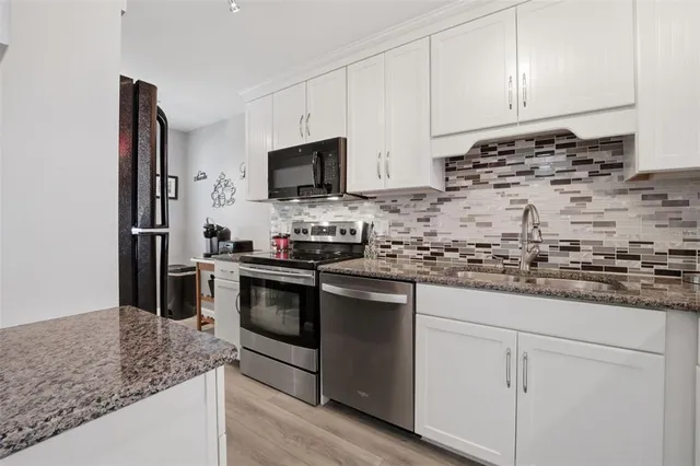 a kitchen with granite countertop white cabinets and stainless steel appliances