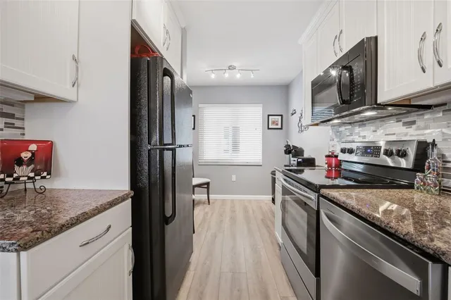 a kitchen with stainless steel appliances granite countertop a sink stove microwave and refrigerator
