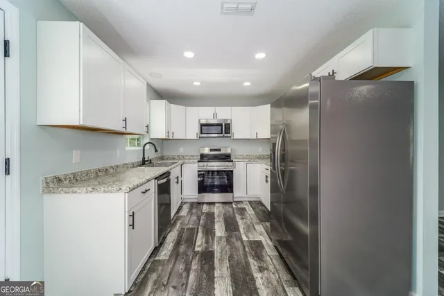 a kitchen with granite countertop white cabinets and a window