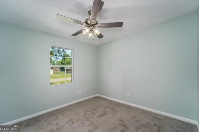 an empty room with a window and a fan