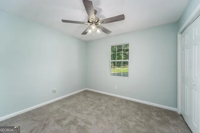 an empty room with a ceiling fan and a window