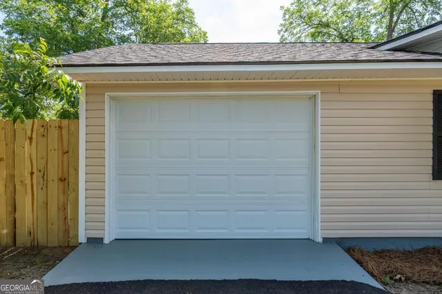 a backyard of a house with plants and large tree