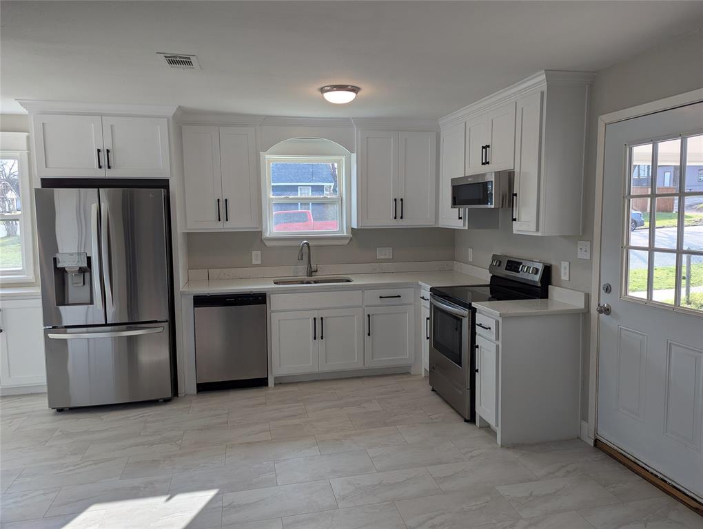 100 West Hull Street Denison, TX 75021 - Photo 5 of 28 a kitchen with a sink white cabinets and stainless steel appliances