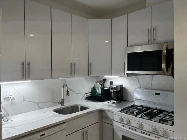 a kitchen with granite countertop a sink a stove and cabinets