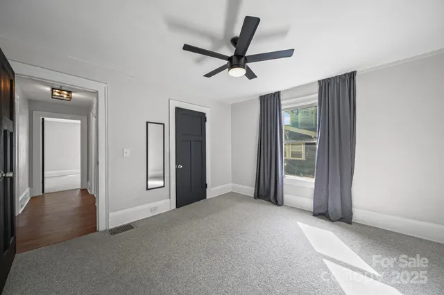 a view of a livingroom with a ceiling fan & windows