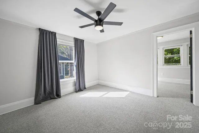an empty room with windows and ceiling fan
