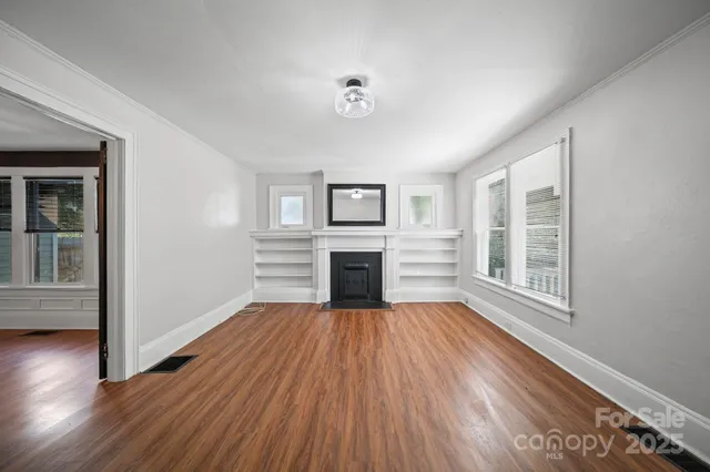 a view of a livingroom with wooden floor fireplace and windows