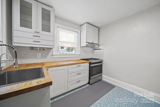 a kitchen with stainless steel appliances granite countertop a sink and a stove next to a window