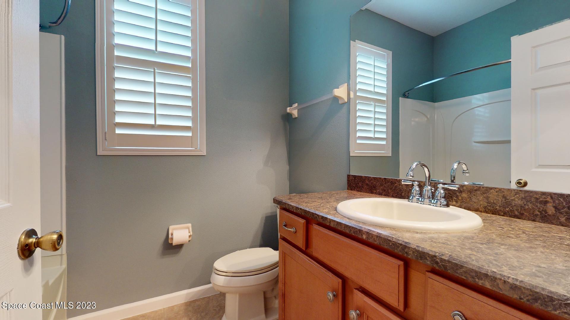 3151 Arden Circle Melbourne, FL 32934 - Photo 26 of 32 a bathroom with a sink a toilet a mirror and a window