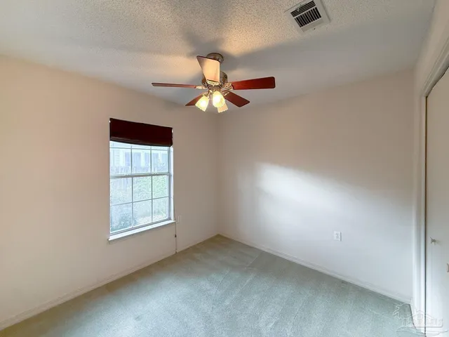 an empty room with windows and fan