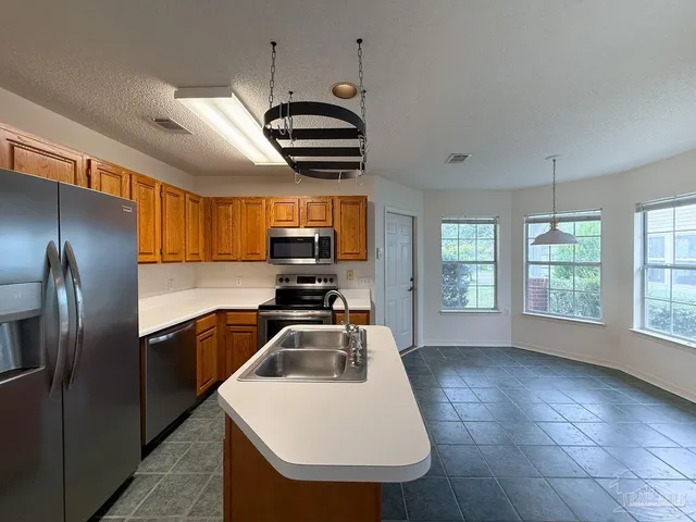 a kitchen that has a sink stainless steel appliances and window