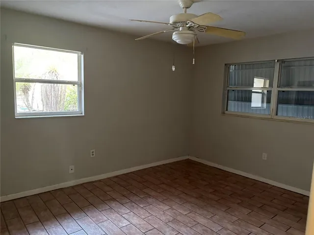en empty room with wooden floor and windows