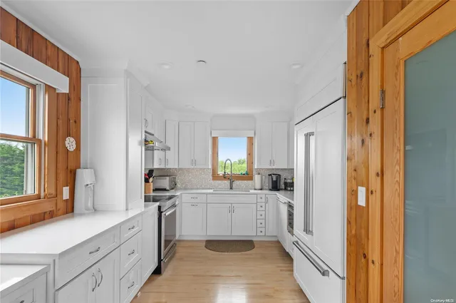 a kitchen with a sink a counter top space stainless steel appliances cabinets and a window