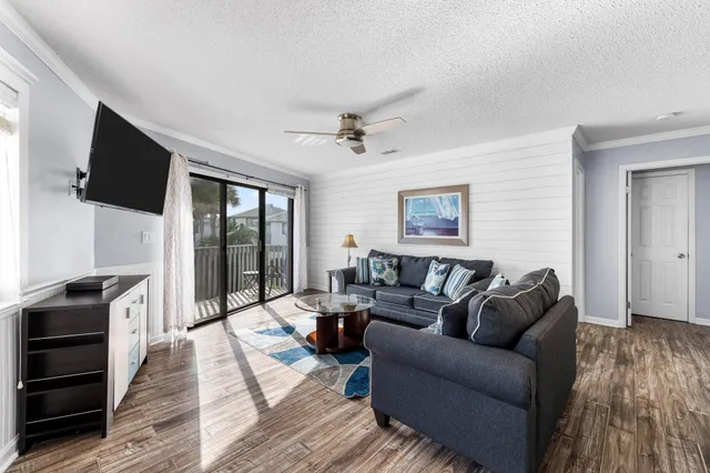 a living room with furniture a flat screen tv and a floor to ceiling window