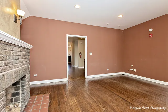 a view of an empty room with wooden floor and a fireplace