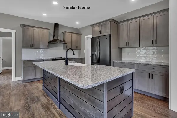 a kitchen with kitchen island granite countertop a sink and refrigerator